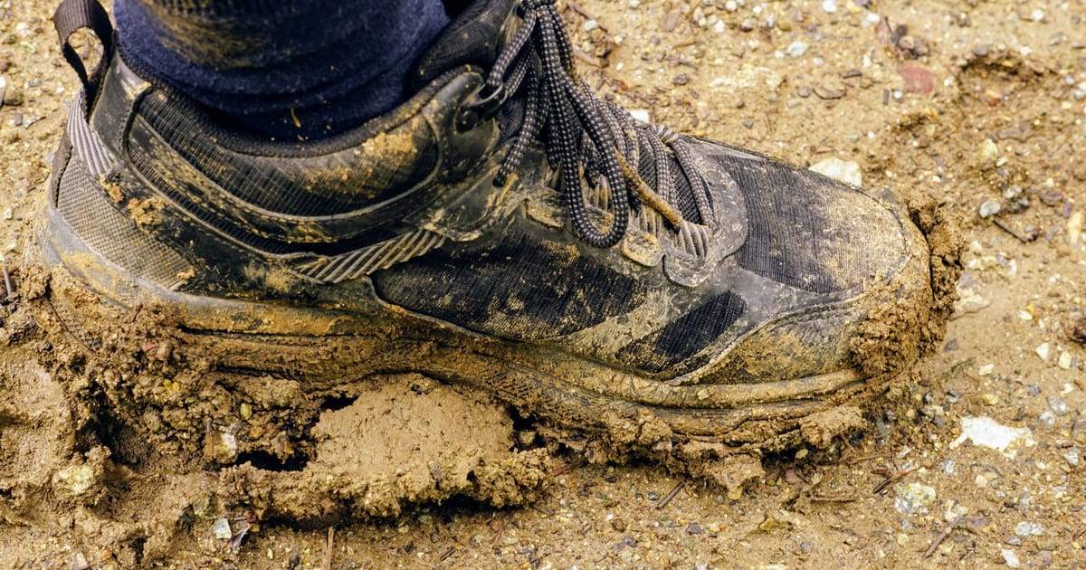 A pair of mud-caked trail shoes drying on a doorstep.