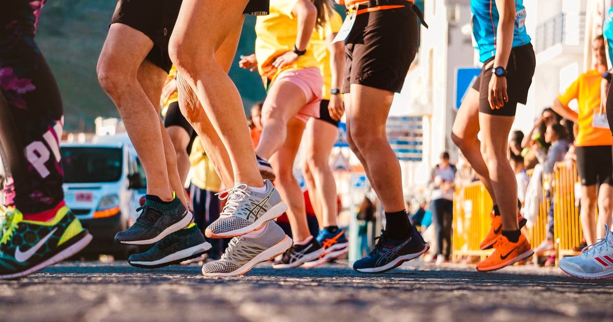 A pair of plated racing shoes on a start line in early light.