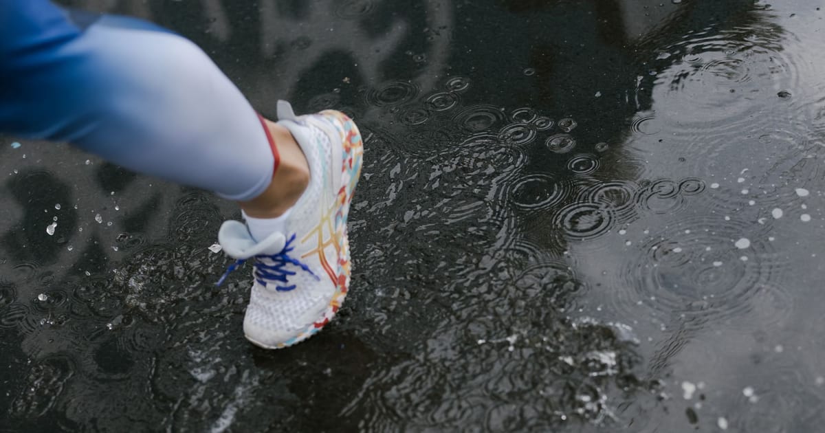 A pair of road running shoes on wet tarmac at first light.