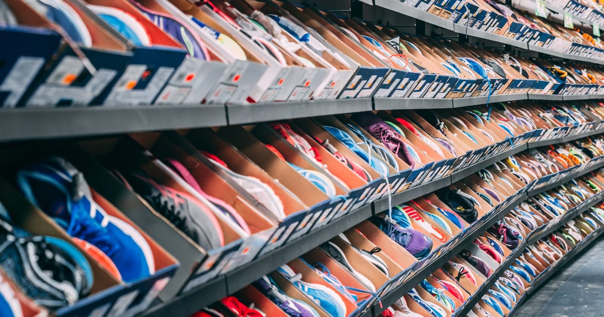 A wall of running shoes on a shop rack, price labels facing out.