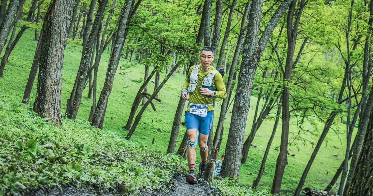A runner descending a rocky forest trail in low autumn light.
